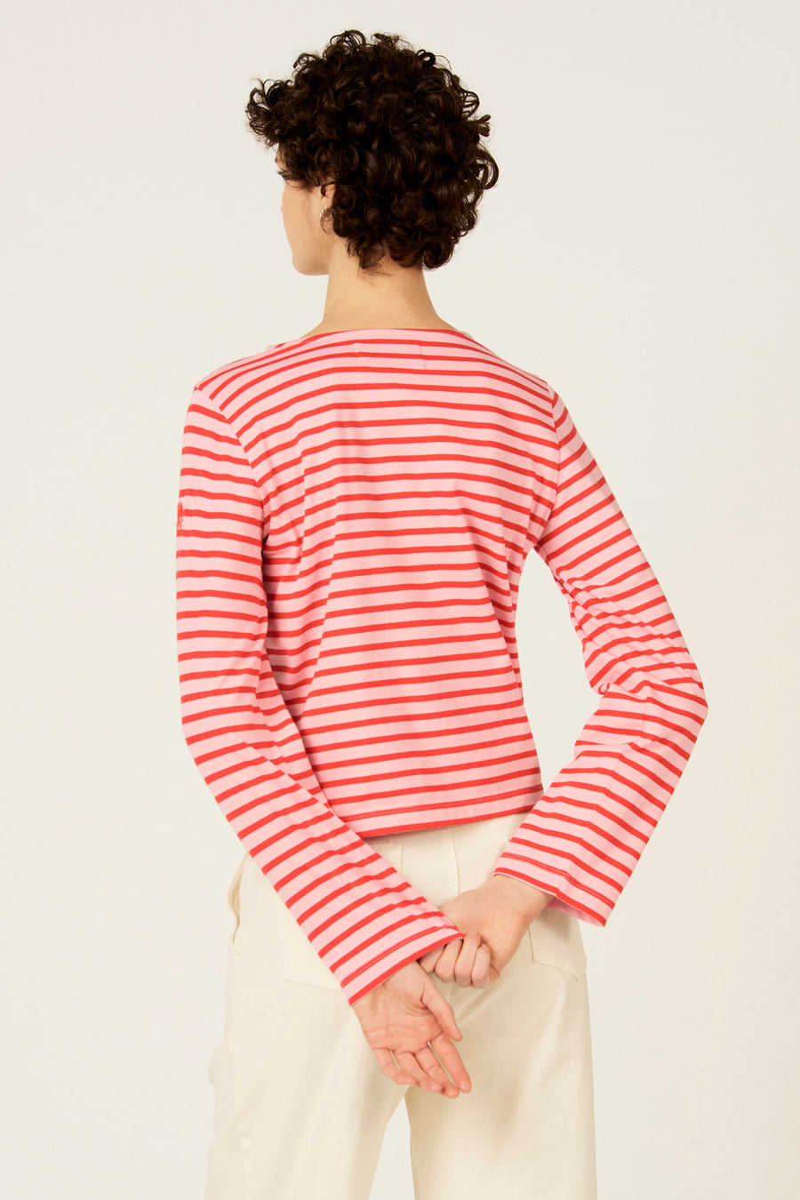 T-shirt à manches longues rayé rouge de Le Fabuleux Marcel de Bruxelles, vu de dos, combiné avec un pantalon de couleur crème.