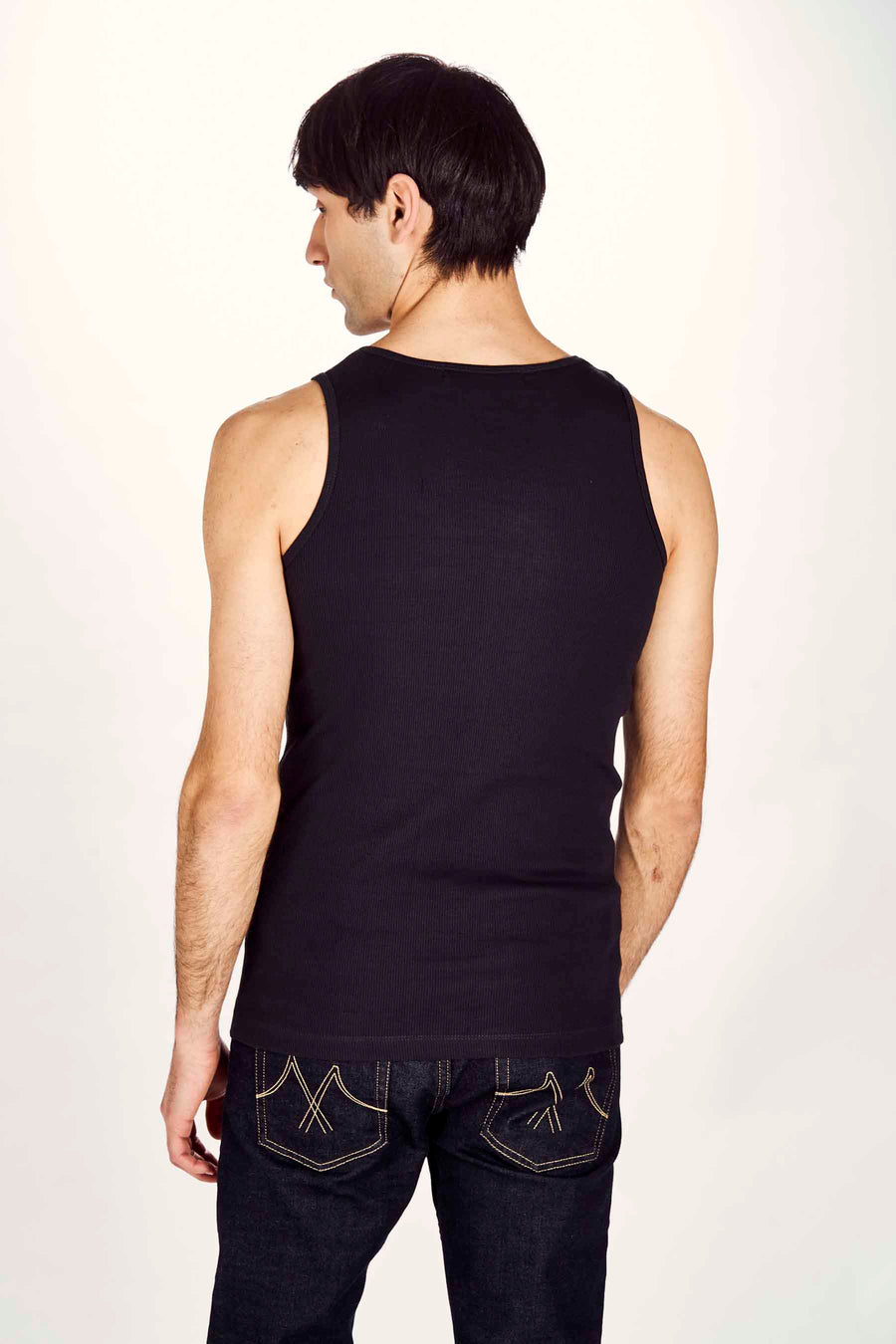 Zwart tanktop van Le Fabuleux Marcel de Bruxelles, geribbelde textuur, gezien van achteren met donkere jeans.
