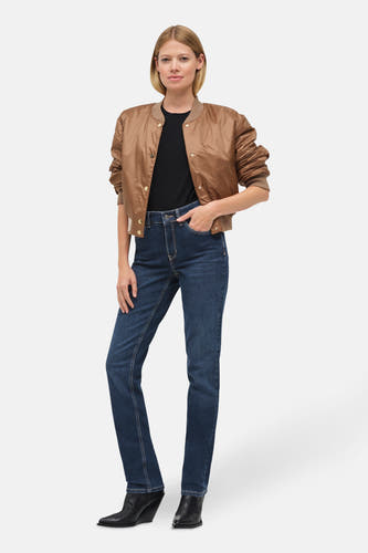 Jean droit en denim bleu, de MAC, associé à un t-shirt noir et une veste bomber marron.