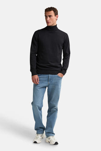 Pull noir avec col montant de Petrol Industries, porté avec des jeans et des baskets blanches.