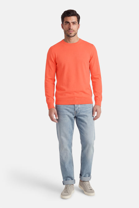 Koraalkleurige trui met ronde hals van Petrol Industries®, gedragen met lichte jeans en grijze sneakers.