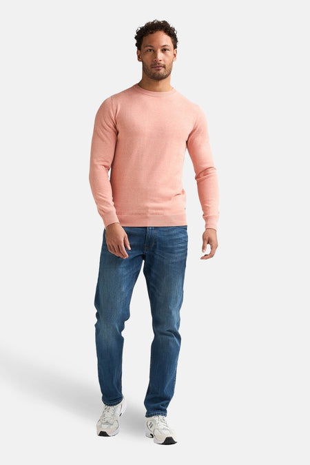 Pull rose à col rond de Petrol Industries, combiné avec un jean bleu et des baskets blanches.