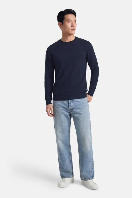 Blauwe trui met ronde hals van Petrol Industries®, gedragen met lichte jeans en witte sneakers.
