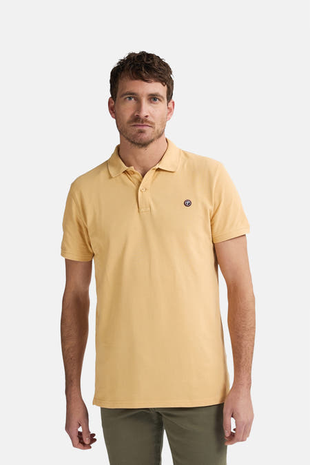 Polo jaune avec manches courtes de Petrol Industries®, vu de derrière, associé à des shorts verts et des chaussures blanches.