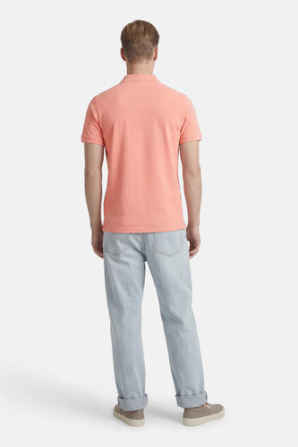 Polo rose à manches courtes de Petrol Industries, vue de dos, avec un jean bleu clair et des chaussures beiges.