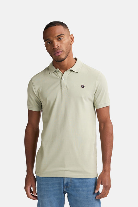 Polo vert de manches courtes de Petrol Industries®, avec logo sur la poitrine, porté avec un jean.