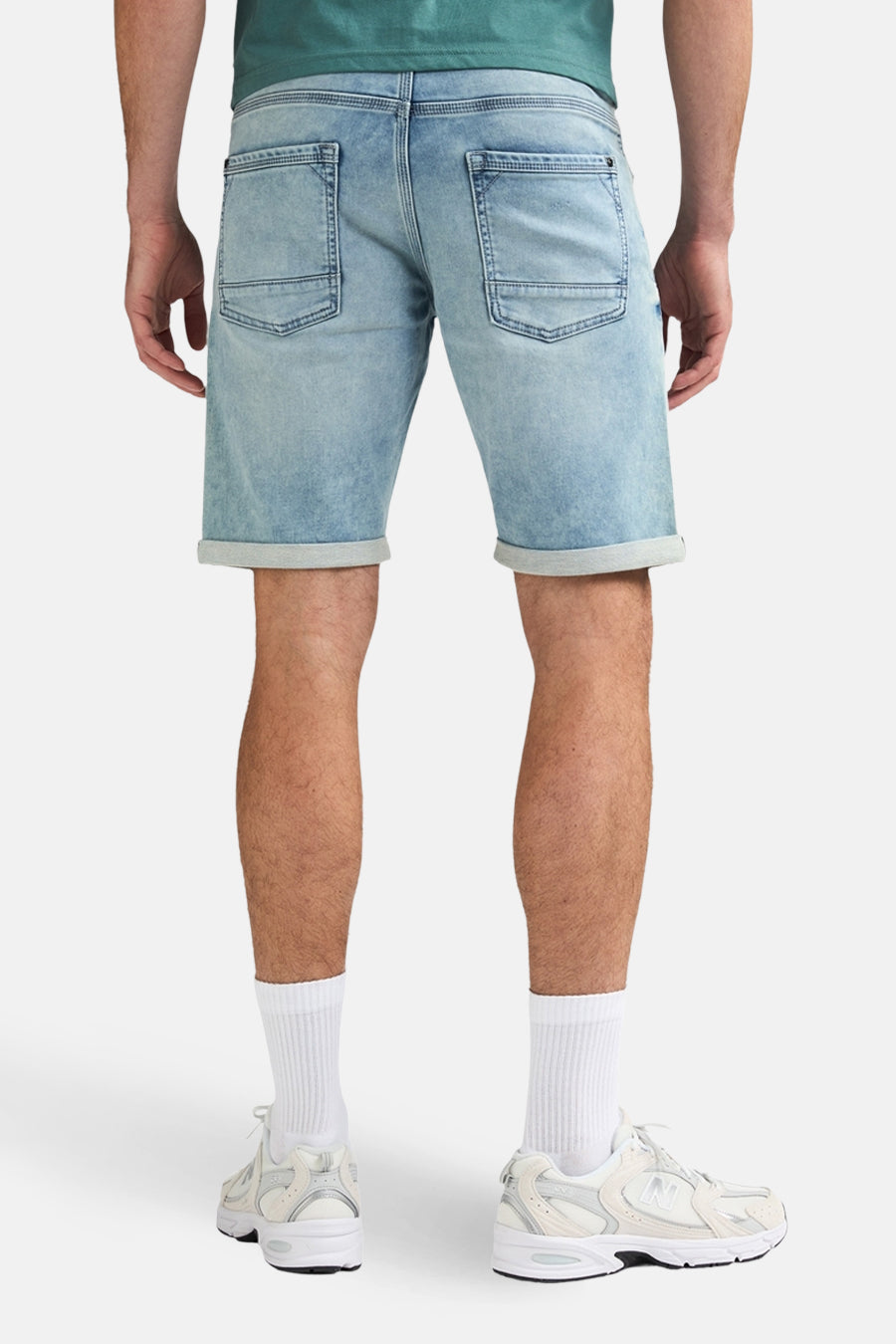 Short en jean bleu clair de Petrol Industries®, avec poches au dos et ourlets retroussés, combiné avec des chaussettes blanches et des baskets.