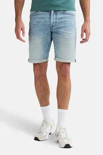 Lichtblauwe denim jeansshort van Petrol Industries® met opgerolde pijpen en witte sokken met sneakers.
