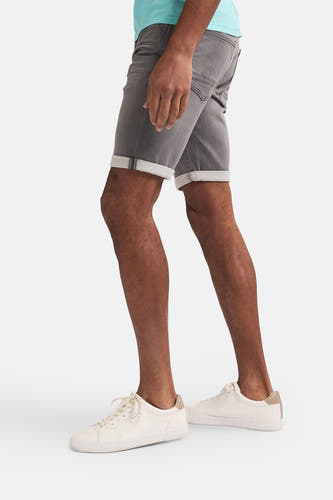 Jean short gris de Petrol Industries, avec un zip sur le côté, porté avec des baskets blanches et une chemise bleu clair, vue latérale.