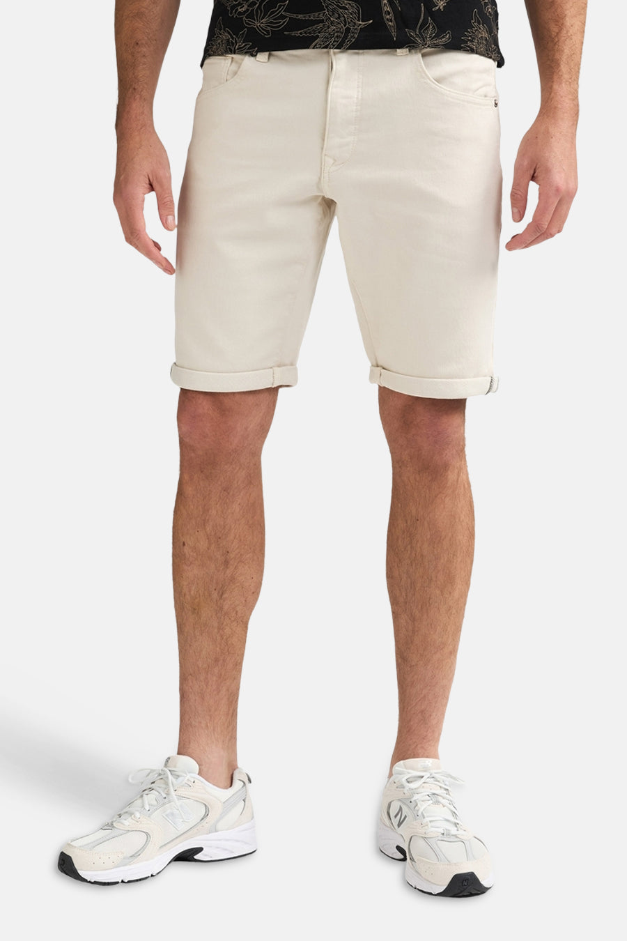 Short écru de Petrol Industries avec ourlets retroussés, porté par un homme avec une chemise foncée et des baskets blanches.