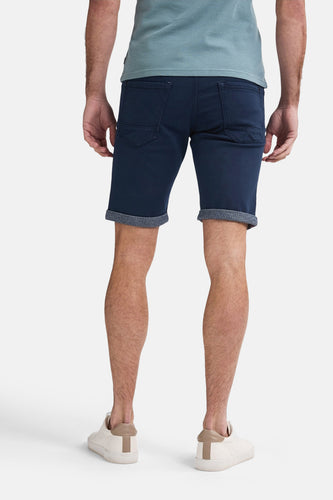 Achterkant van een man in blauwe shorts en witte sneakers.