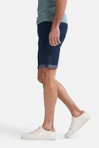 Persoon met blauwe shorts en witte sneakers.
