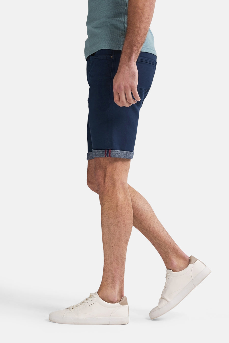 Persoon met blauwe shorts en witte sneakers.