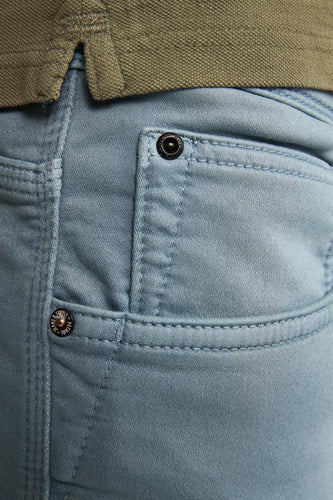 Close-up lichtblauwe broek met zak en groene polo.