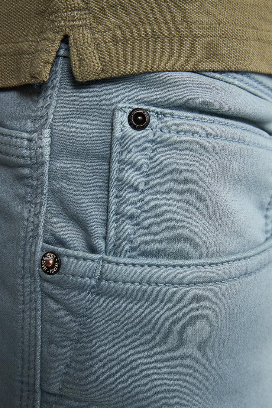 Close-up lichtblauwe broek met zak en groene polo.