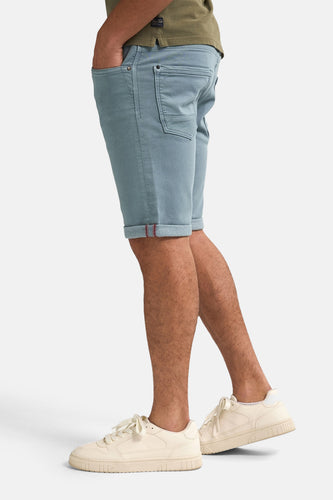 Man met blauwe shorts en crèmekleurige sneakers.