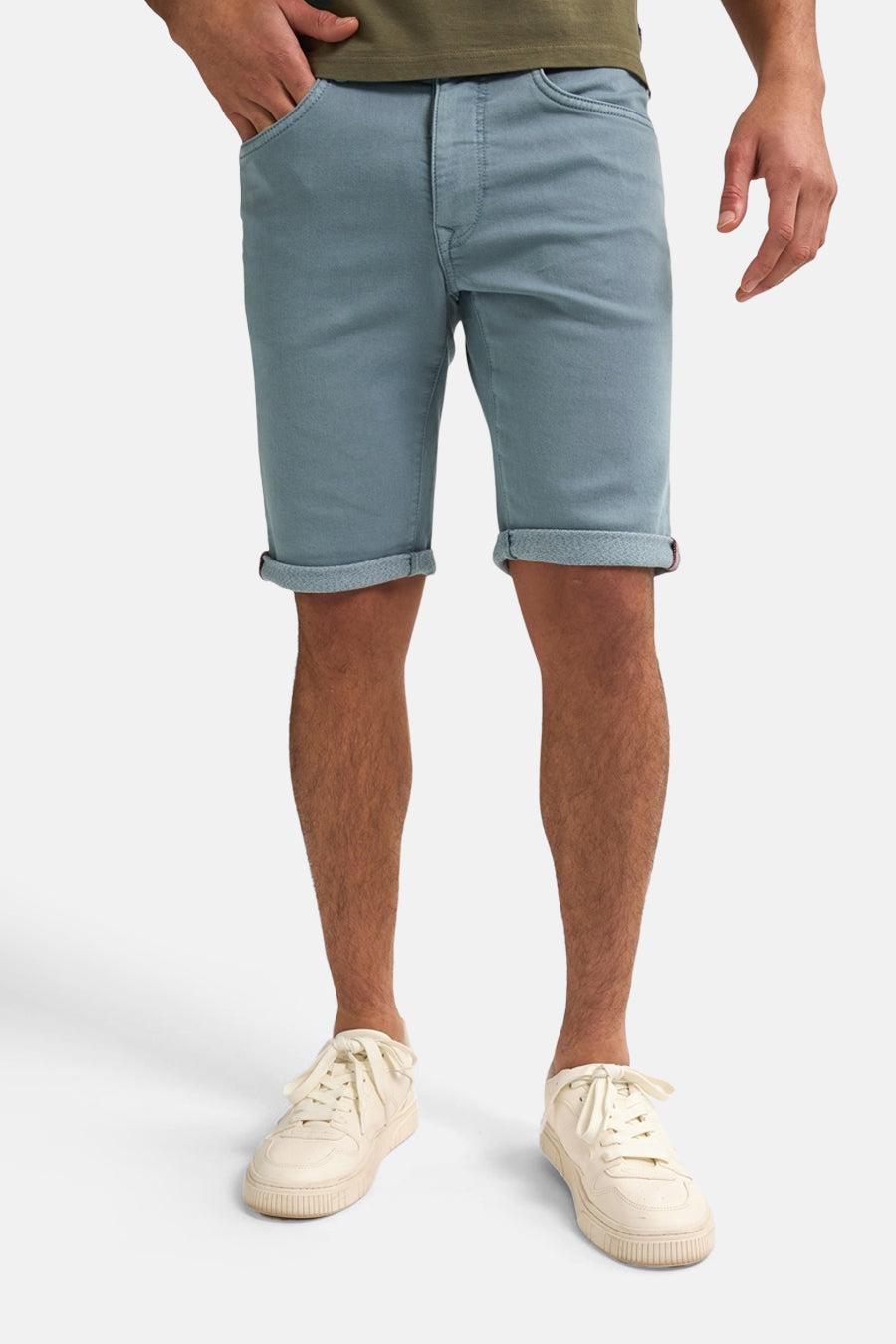 Man in blauwe shorts en crèmekleurige sneakers.