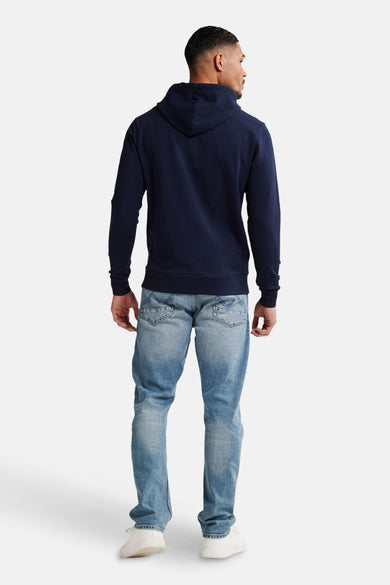 Pull-over bleu avec capuche de Petrol Industries®, dos, combiné à des jeans légers et des baskets blanches.