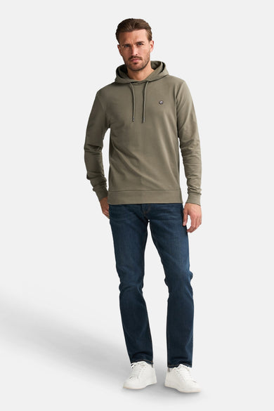 Sweater vert de Petrol Industries Industries avec capuche, des cordons et des jeans bleu marine simples, ainsi que des baskets blanches.