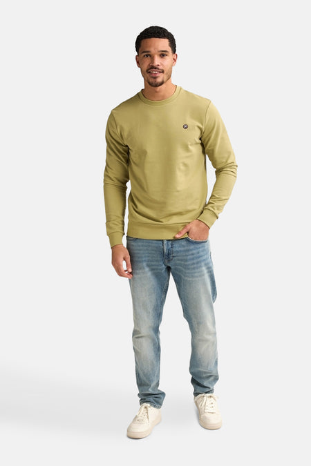 Sweater vert de Petrol Industries® porté avec un jean bleu et des baskets blanches.