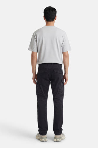 Pantalon cargo noir de Petrol Industries, avec poches et un look décontracté, combiné avec un t-shirt gris et des baskets.