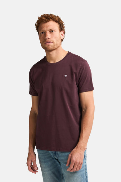 T-shirt Bordeaux à manches courtes de Petrol Industries, avec un petit logo sur la poitrine et porté avec un jean.