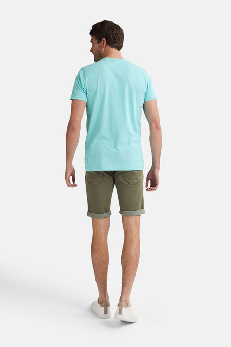 T-shirt bleu à manches courtes de Petrol Industries, vu par derrière, associé à des shorts kaki et des baskets blanches.