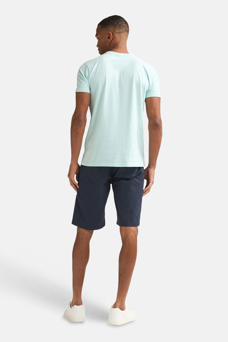 Groen T-shirt van Petrol Industries, gezien van achteren, met korte mouwen en gecombineerd met donkerblauwe shorts en witte sneakers.
