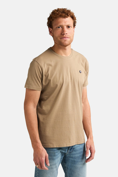 T-shirt écru à manches courtes de Petrol Industries®, avec un petit logo sur la poitrine et porté avec des jeans.