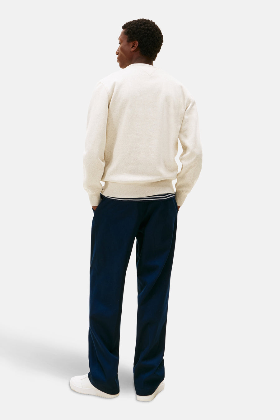 Gilet beige de TOMMY HILFIGER, avec un pantalon bleu marine et des chaussures blanches.