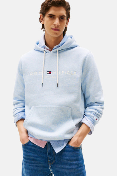 Sweat-shirt bleu de TOMMY HILFIGER, porté sur une chemise et associé à des jeans.