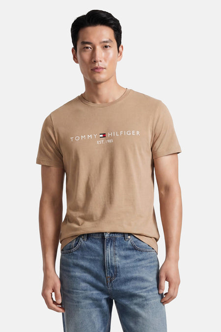 Beige korte mouwen T-shirt van TOMMY HILFIGER met wit logo en gestreept embleem, gedragen met blauwe jeans, front view