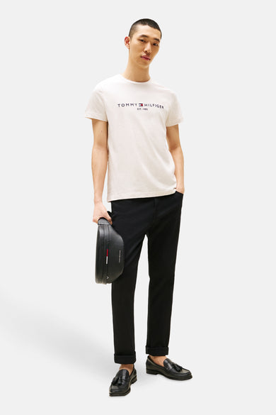 T-shirt beige à manches courtes de Tommy Hilfiger, porté avec un pantalon noir et des loafers en cuir.