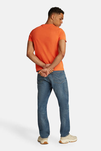 Oranje T-shirt met korte mouwen van TOMMY HILFIGER, met achter aanzicht en gecombineerd met blauwe jeans en beige sneakers.
