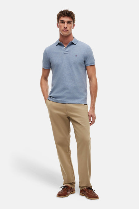 Polo bleu TOMMY HILFIGER à manches courtes et boutons, porté avec un pantalon kaki et des chaussures marron.