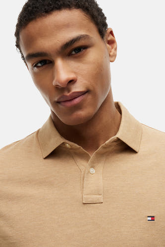 Beige polo van TOMMY HILFIGER met pique textuur, klassieke kraag, twee knopen en het merklogo op de borst.
