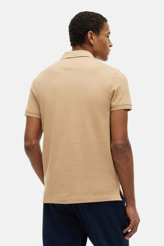 Polo beige de TOMMY HILFIGER, vue de dos, avec une texture fine, portée par un homme avec un pantalon bleu foncé.