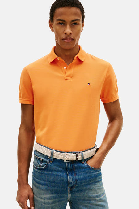 Polo orange à manches courtes de Tommy Hilfiger, avec un petit logo sur la poitrine, porté avec un jean et des bottines.