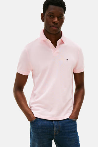 Polo rose à manches courtes de TOMMY HILFIGER, vu de derrière, associé à des jeans bleus marine et des loafers marrons.