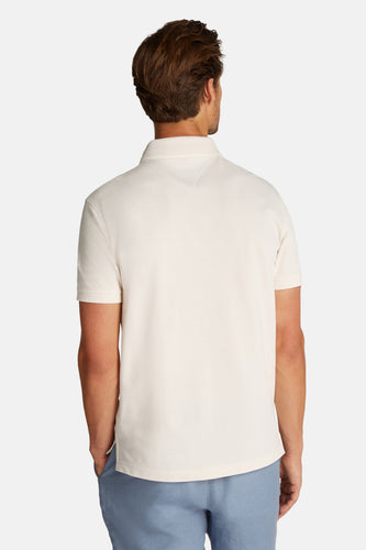 Man van achteren in gebroken witte polo en blauwe broek.