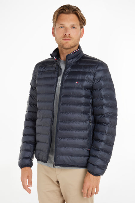 Veste de pluie bleue de TOMMY JEANS, avec des coutures horizontales, sur un modèle portant un t-shirt gris et un pantalon kaki.