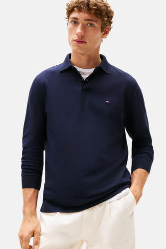 Polo bleu de TOMMY HILFIGER, avec des manches longues et un petit logo sur la poitrine, porté avec un t-shirt blanc.