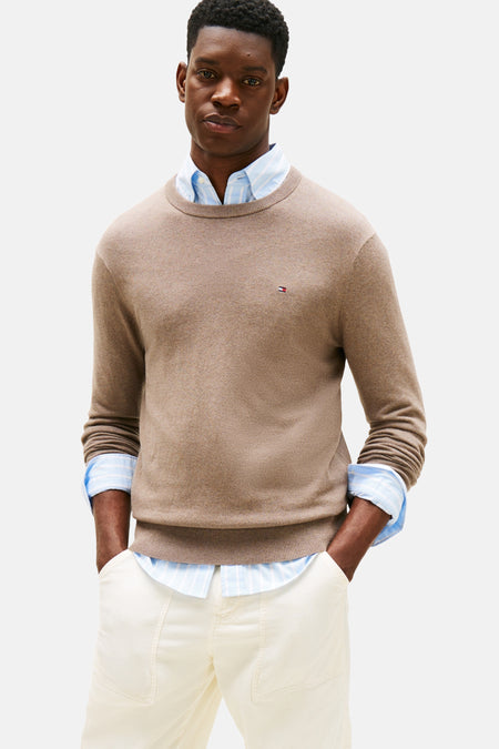 Gilet beige à col rond de TOMMY HILFIGER, porté sur un chemisier rayé et un pantalon blanc.