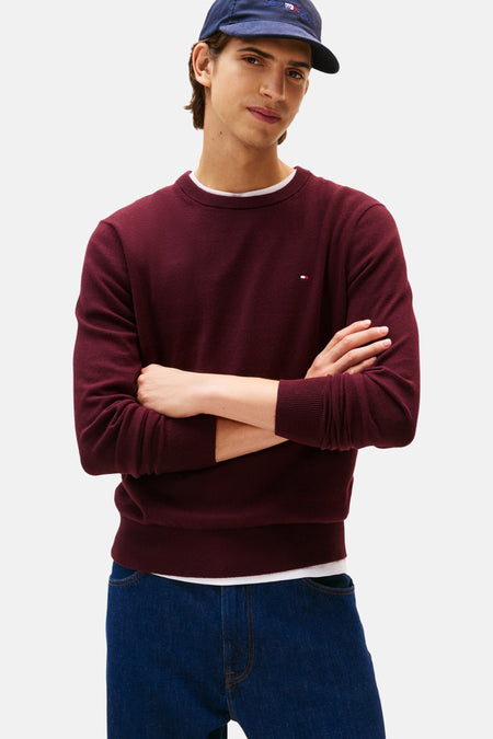 Sweat-shirt bordeaux avec col rond de TOMMY HILFIGER, à manches croisées et jeans bleu marine.
