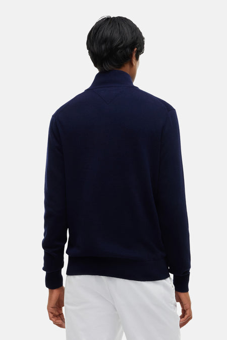 Pull à col roulé bleu marine TOMMY HILFIGER, vue arrière, coupe ajustée, texture tricotée, pantalon blanc.
