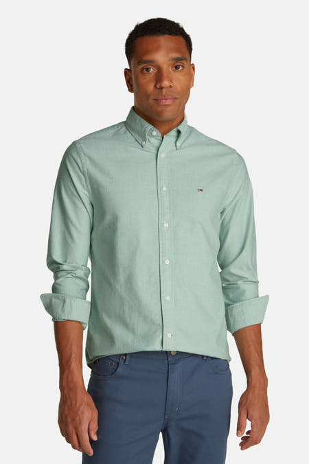 Chemise verte à manches longues de Tommy Hilfiger avec col boutonné et pantalon bleu.