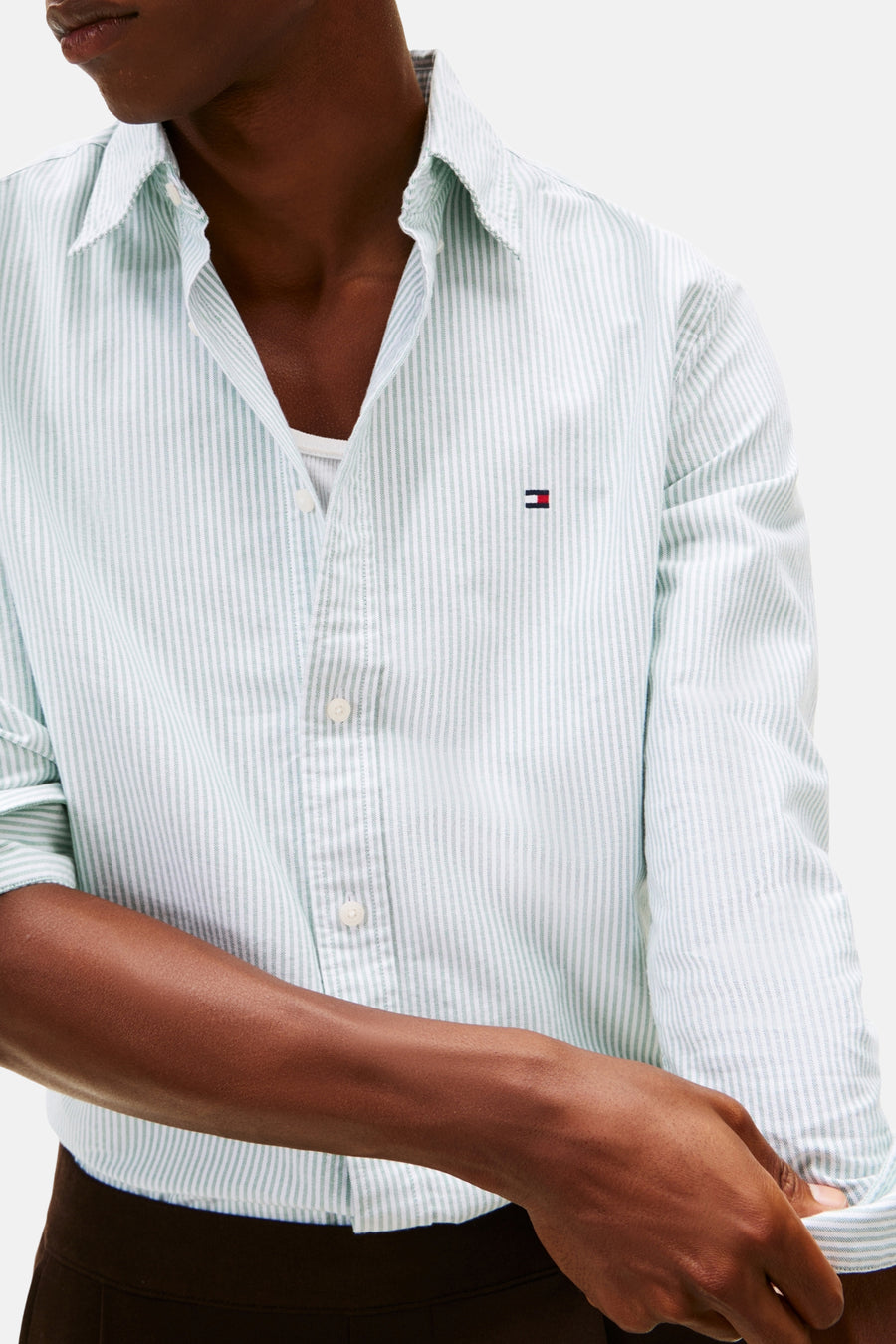 Chemise rayée verte de TOMMY HILFIGER à manches longues, partiellement déboutonnée et portée sur une chemise blanche.