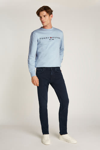 Blauwe zwarte denim straight jeans van TOMMY HILFIGER, gecombineerd met een lichtblauw sweatshirt en witte sneakers.
