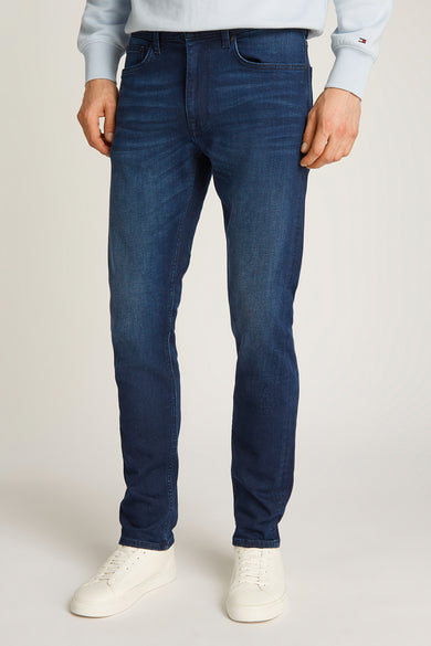 Jean droit de denim bleu marine de Tommy Hilfiger, avec un lavage clair et des baskets blanches.