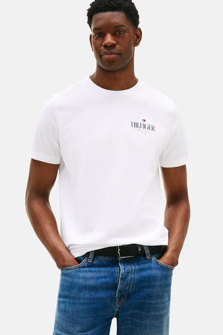 T-shirt blanc à manches courtes de TOMMY HILFIGER, vu sur le dos, associé à des jeans bleus et des baskets marrons.